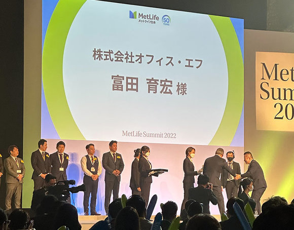 MetLife Summit2022 オフィス・エフ代表の富田が壇上で表彰されています