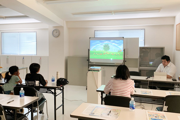 セミナー開催日の様子。会場に参加者とオフィス・エフのスタッフが座っている。会場の前方にはホワイトボードがあり、そこにスライドの画面が写っている。