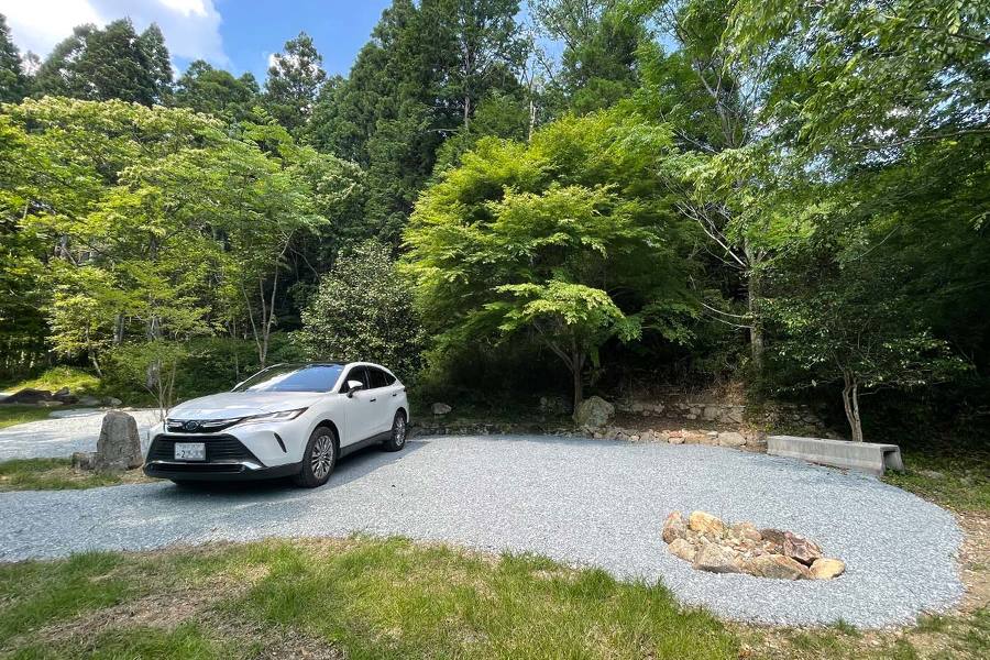 区画Aに車が停まっている画像。晴れた空の下、森の中に整地された空間がある。右には焚火場がある。