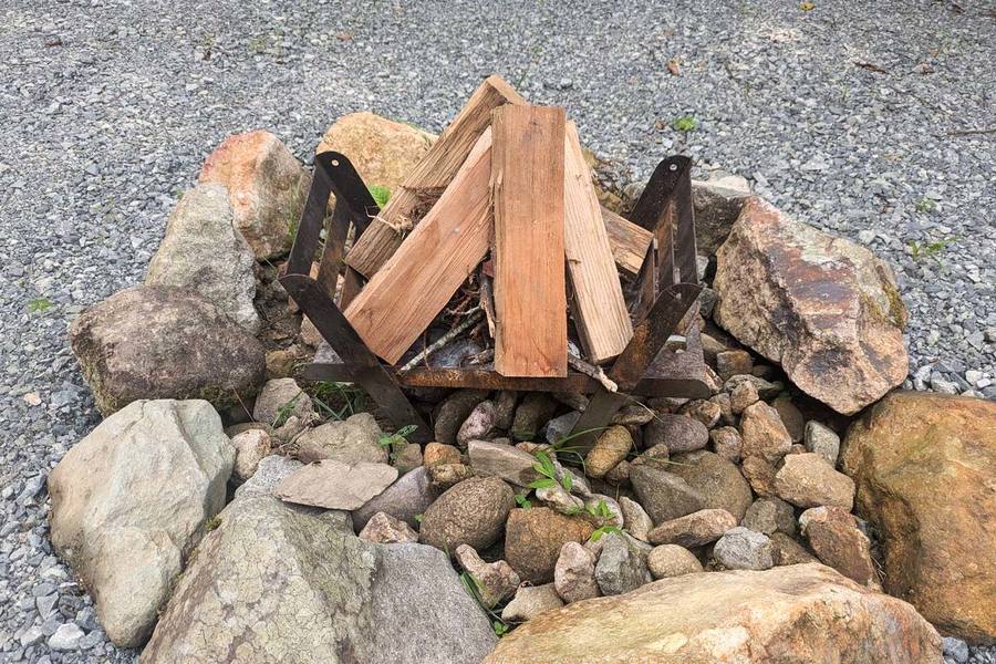 焚火場に焚き火台が置かれ、その上に薪が乗っている。